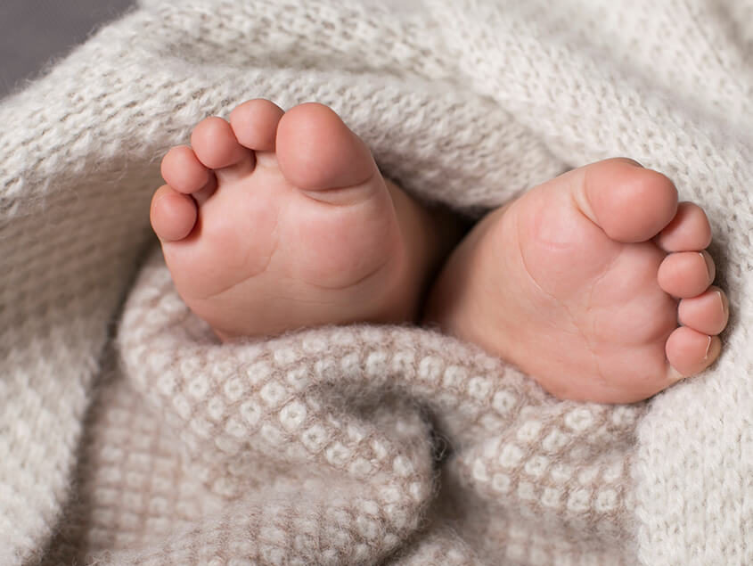 Baby's feet sticking out of Alpaca Wool knitted Blanket
