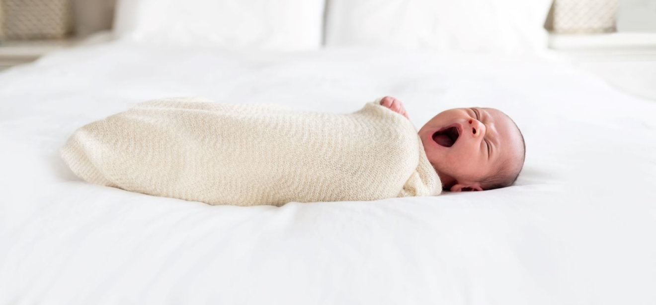 Quality Baby clothes Blog Banner - Baby On A Bed Wrapped In A Blanket
